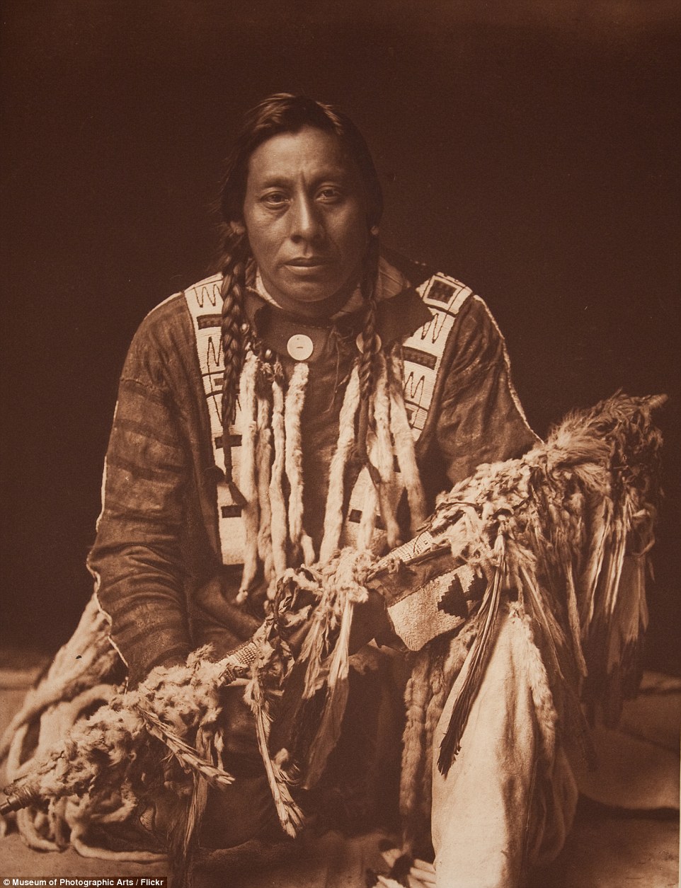 00578-2957360-A_Piegan_man_kneels_holding_medicine_pipe_described_by_Curtis_as-a-6_1424250374455.